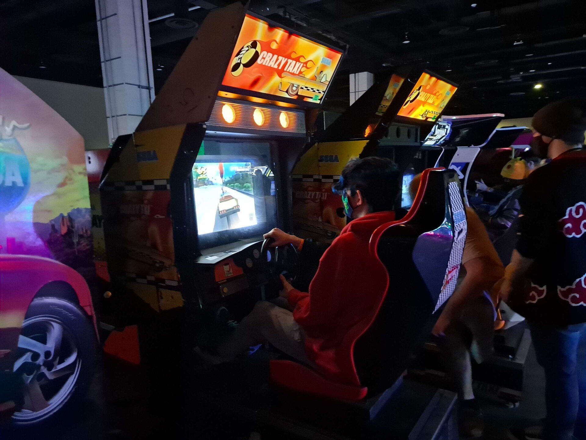 A Crazy Taxi arcade cabinet at MAGFest 2023, someone mid-fare